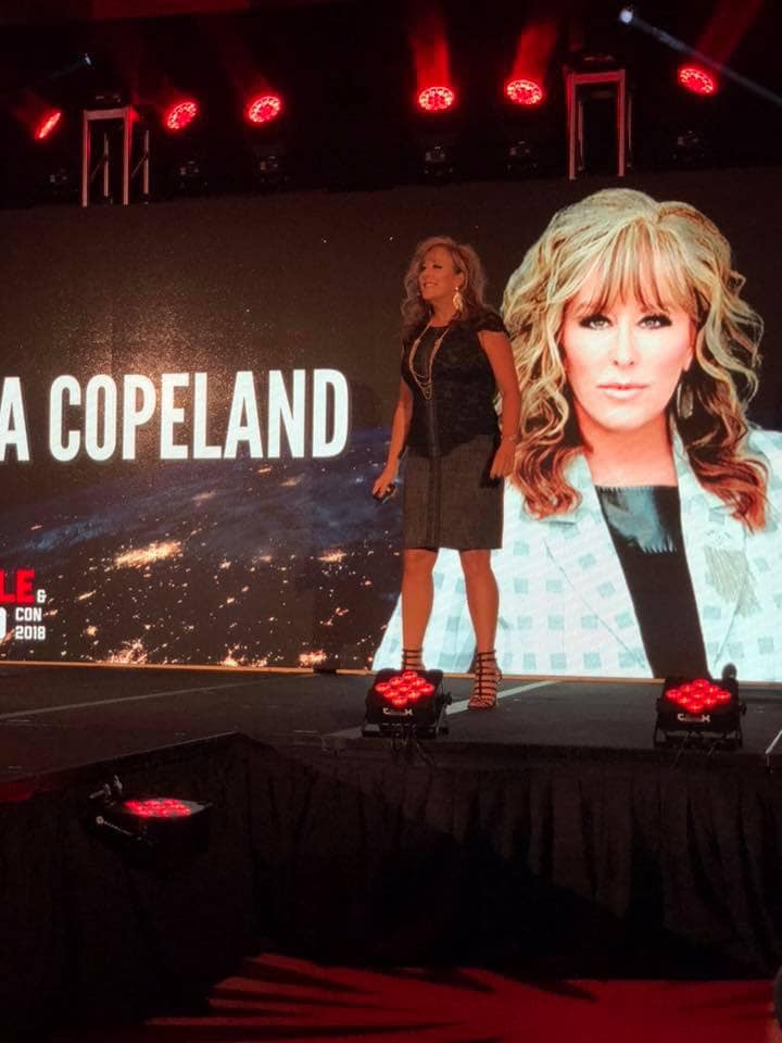 Lisa Copeland delivering a keynote on stage with large projection behind her